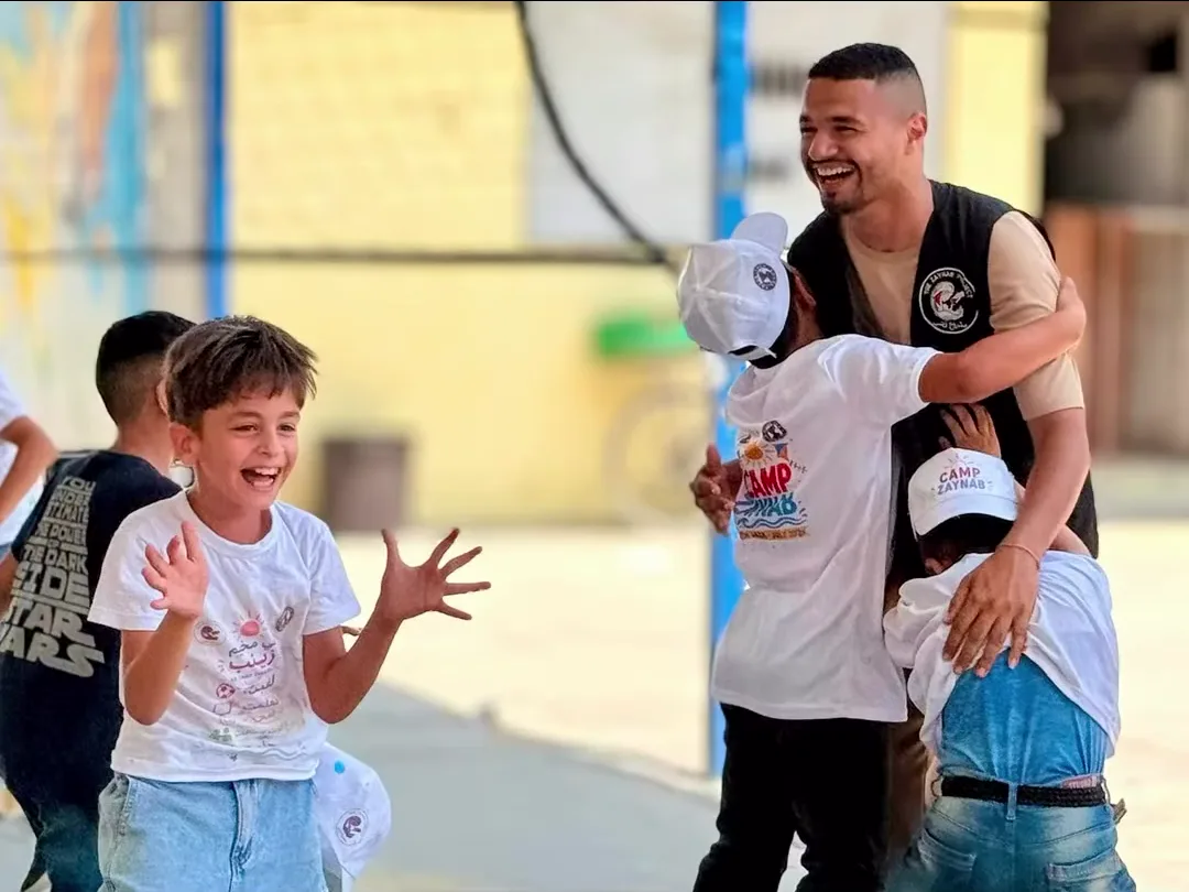 Children laughing with a facilitator during a Camp Zaynab activity